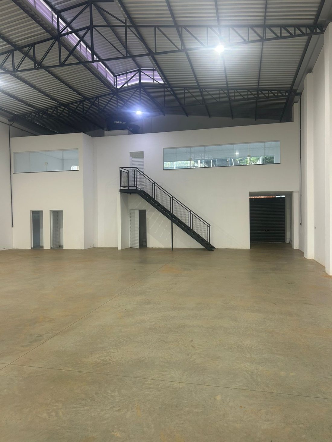 Vista do mezanino com guarda-corpo de vidro sobre a área operacional